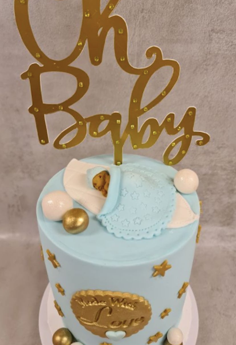 Baby shower cake with sleeping baby on top.