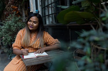 Young woman sitting at table wondering what things she should write in her secret diary.