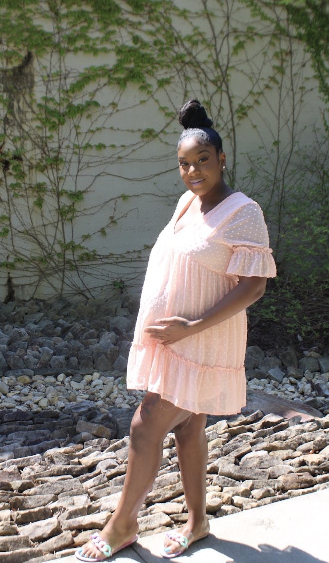 a woman outside wearing a mini pink swiss dot maternity dress with sleeves