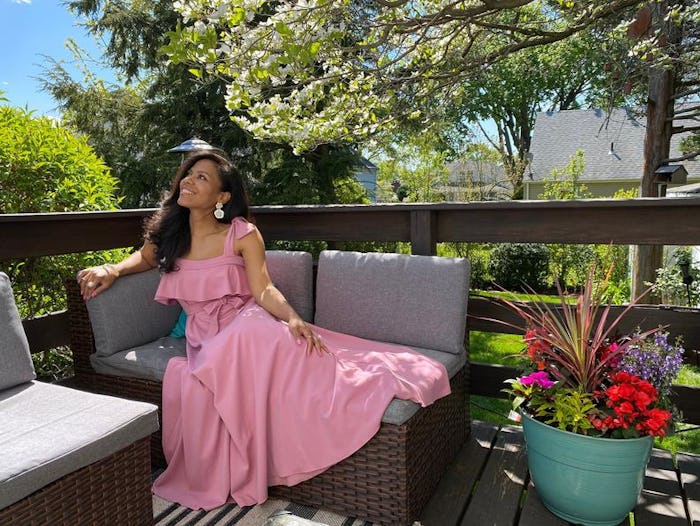 a woman wearing a pink baby shower dress sitting on a bench outside