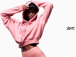 Model wears pink cropped hoodie and leggings from Reebok x Victoria Beckham Drop 5, releasing on Jul...