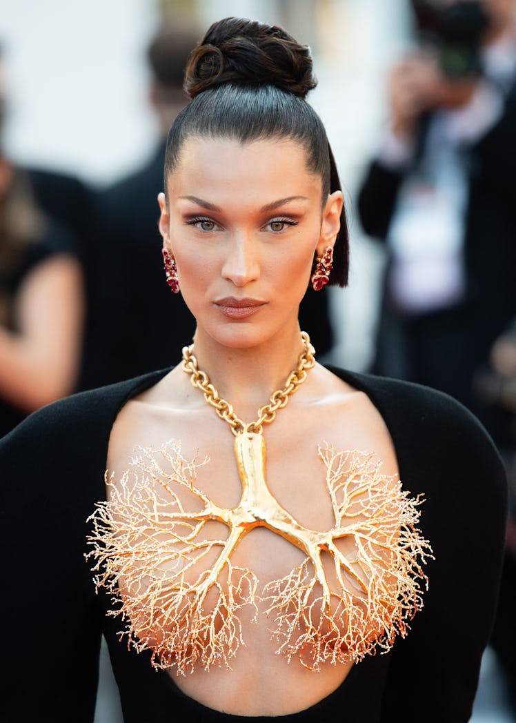 Bella Hadid in a black Schiaparelli dress with a golden lung-shaped necklace at the Cannes Film Fest...