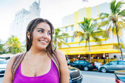 Young woman smiling on the streets of Miami Beach before posting a selfie on Instagram with a Miami ...