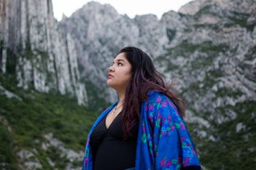 Young woman at the top of a mountain, waiting to post on Instagram with view captions.