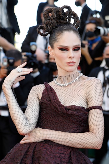 Coco Rocha in a grown asymmetric gown and mesh fishnet shirt at the Cannes Film Festival 2021