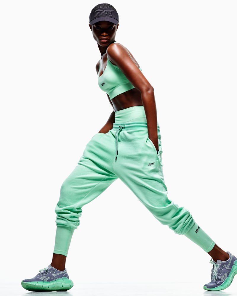Model wears minty green sports bra, shorts, and sweatpants from Reebok x Victoria Beckham Drop 5, re...