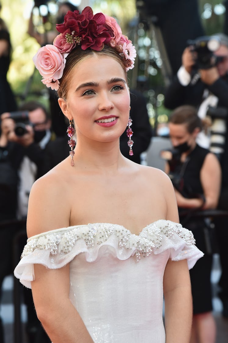 Haley Lu Richardson in a white off-the-shoulder dress and a floral crown at the Cannes Film Festival...