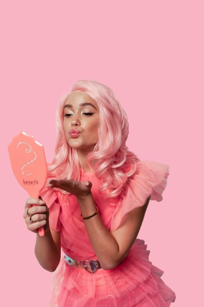 Model and TikToker Olivia Ponton wears a pink wig and blows a kiss into a handheld mirror in a promo...