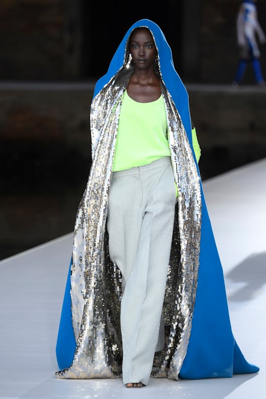A model in a blue-silver sequin cape, lime top and grey pants at the Valentino Couture Fall 2021 Cou...