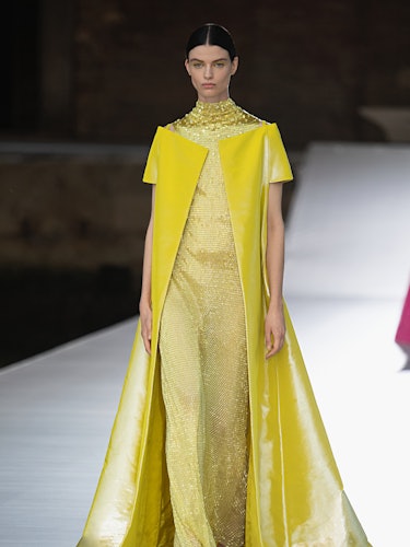 A model in a gold sequin dress and a yellow leather cape at the Valentino Couture Fall 2021 Couture