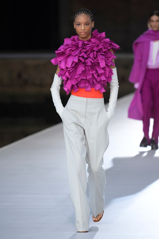 A model in a pink frilled top, white gloves and white-orange trousers at the Valentino Couture Fall ...