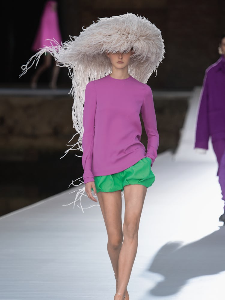 A model in a pink top, green shorts and white hat at the Valentino Couture Fall 2021 Couture