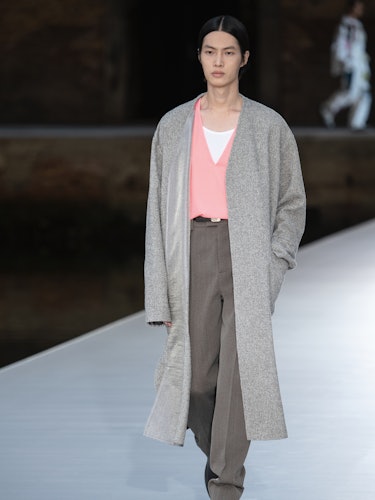 A model in a pink top, grey sweater and brown pants at the Valentino Couture Fall 2021 Couture