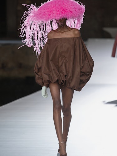 A model in a brown dress and a pink hat at the Valentino Couture Fall 2021 Couture