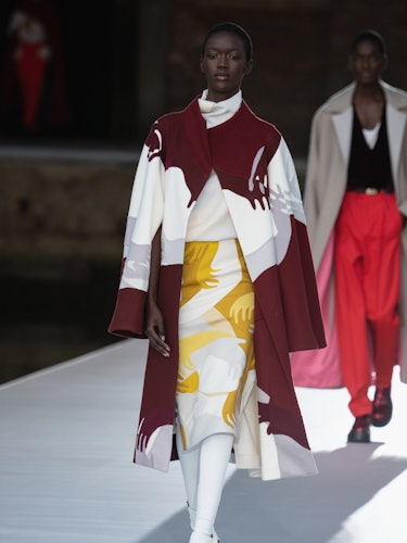 A model in a red-white coat and yellow-white skirt at the Valentino Couture Fall 2021 Couture