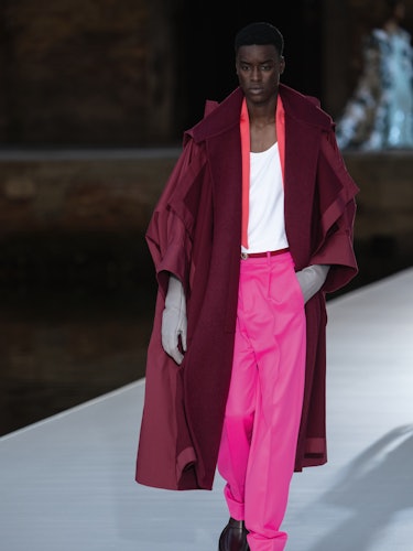 A model in a burgundy coat, white top and pink pant at the Valentino Couture Fall 2021 Couture