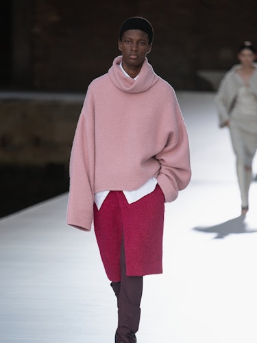 A model in a pink sweater and a red skirt at the Valentino Couture Fall 2021 Couture