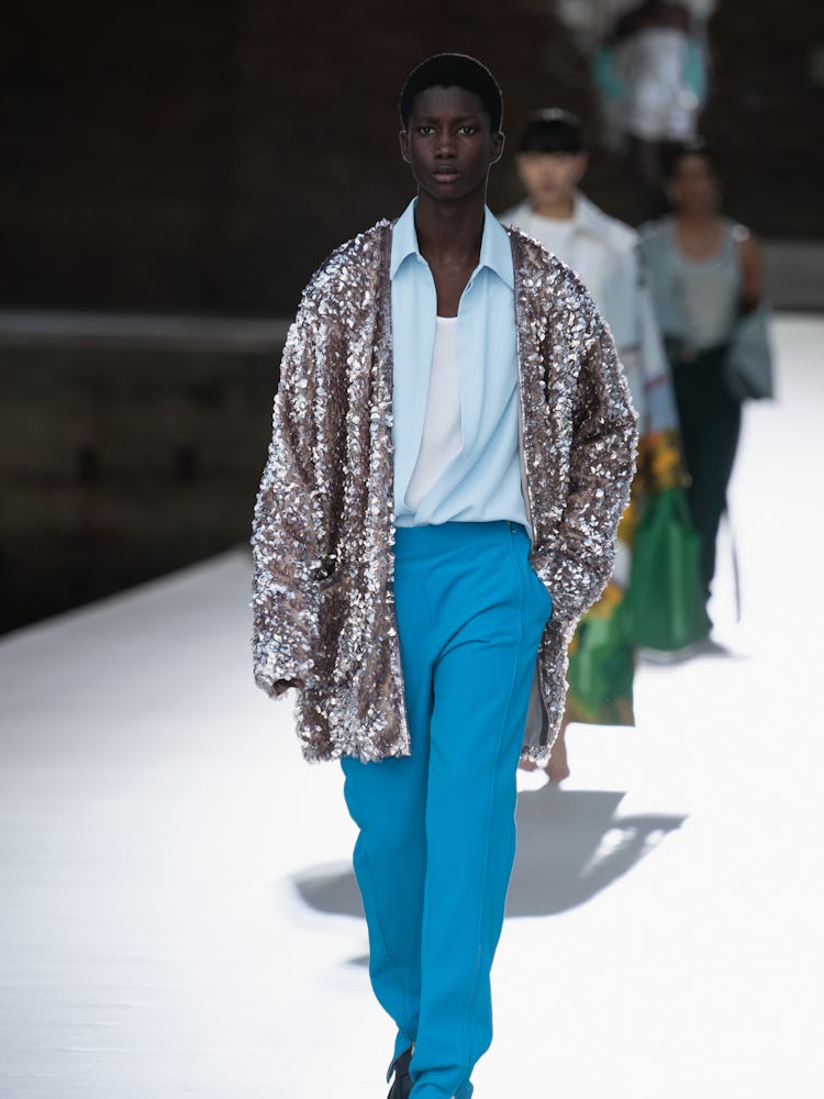A model in a blue shirt and pants and sequin jacket at the Valentino Couture Fall 2021 Couture