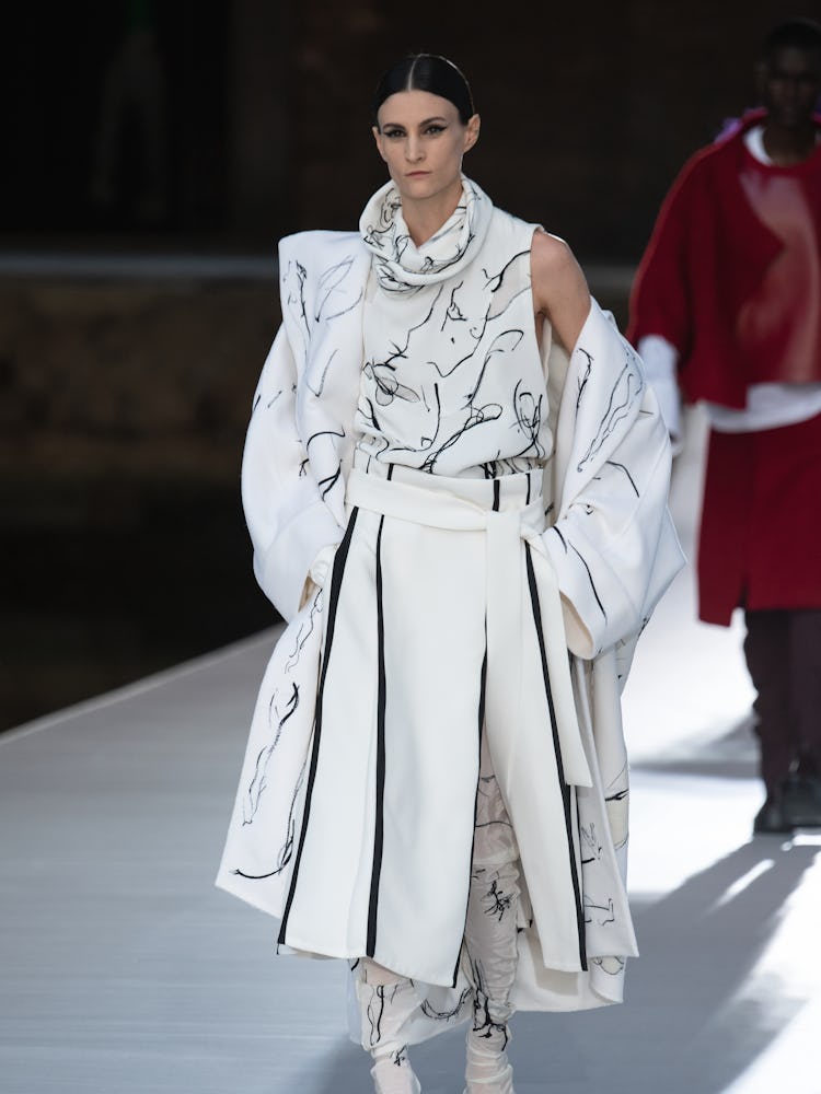 A model in a white-black dress and coat at the Valentino Couture Fall 2021 Couture