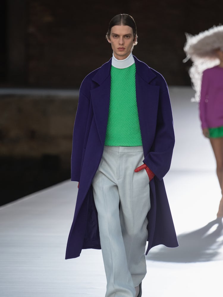 A model in a green top, navy coat and grey pants at the Valentino Couture Fall 2021 Couture