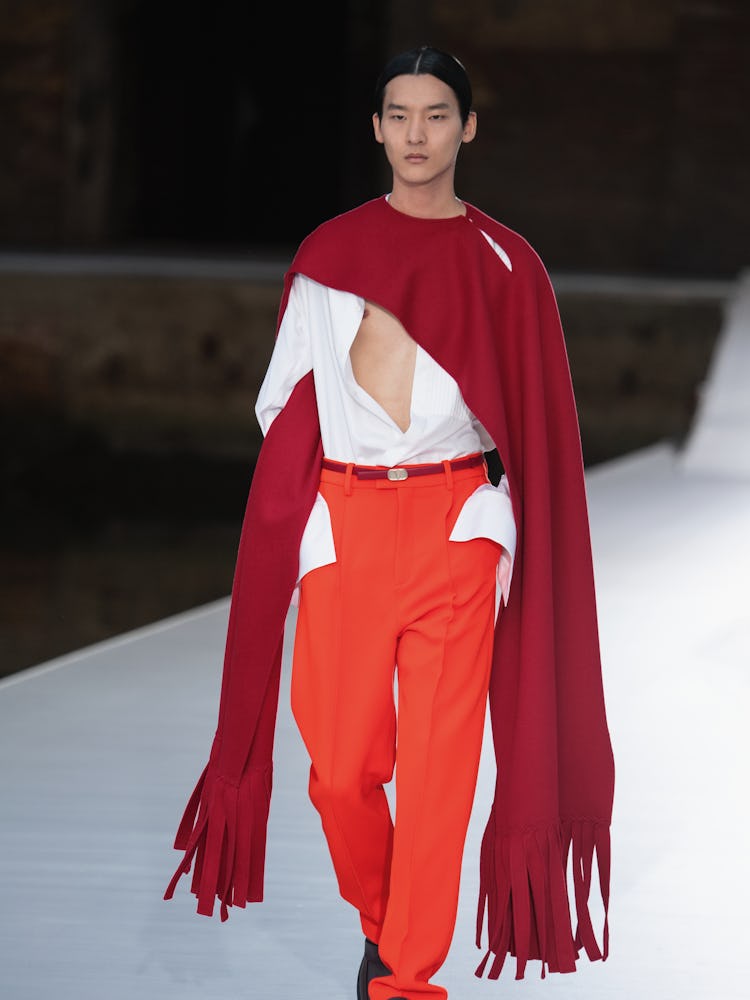A model in a burgundy scarf, white shirt and red pants at the Valentino Couture Fall 2021 Couture