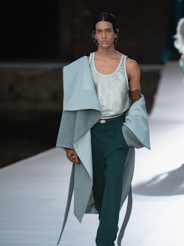 A model in a grey shirt and coat and teal pants at the Valentino Couture Fall 2021 Couture