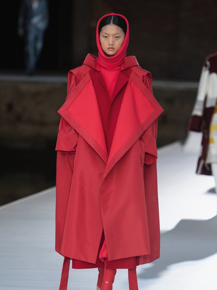 A model in an oversized red hooded coat at the Valentino Couture Fall 2021 Couture
