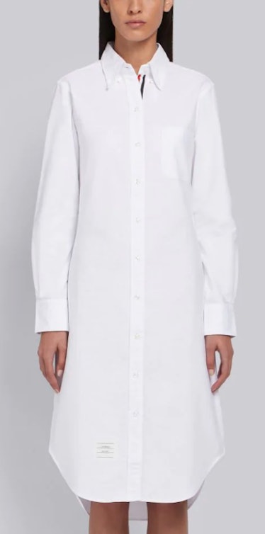 A white knee-length shirt dress with Thom Browne's logo stitching at the neck. 