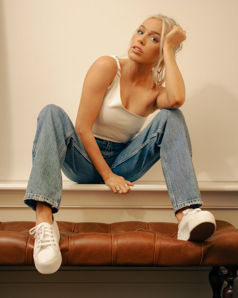 Alex Cooper in a white tank top ad blue denim jeans, the owner of the 'Call Her Daddy' podcast