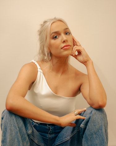 Alex Cooper in a white tank top ad blue denim jeans, the owner of the 'Call Her Daddy' podcast