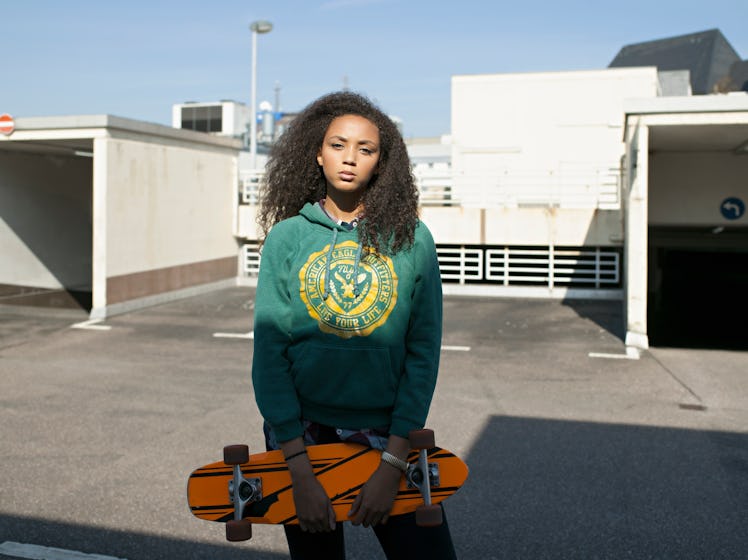 Young woman about to go skateboarding, the Olympic sport she'd most likely compete in, based on her ...