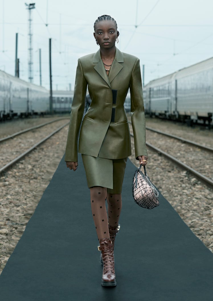 A female model walking while wearing a green Givenchy blazer and skirt combination