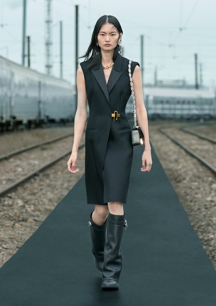 A woman walking while wearing a black Givenchy dress
