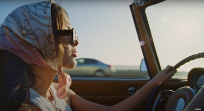 still from olivia rodrigo's deja vu music video, she is driving in a convertible with vintage sungla...