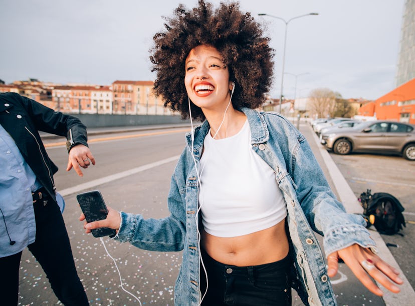 Happy young woman listening to music, having the best August 2021, per her zodiac sign's monthly hor...