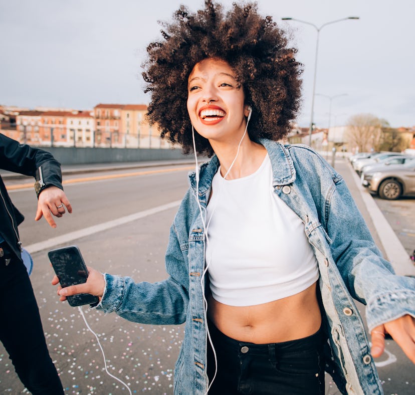 Happy young woman listening to music, having the best August 2021, per her zodiac sign's monthly hor...