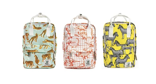 Three backpacks in a row; one with tiger print, one with dino print, one with zebra print