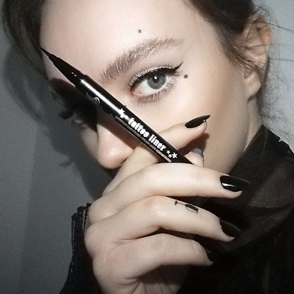 A woman covering her face while holding the KVD Beauty’s Tattoo Liner, only revealing her eye makeup