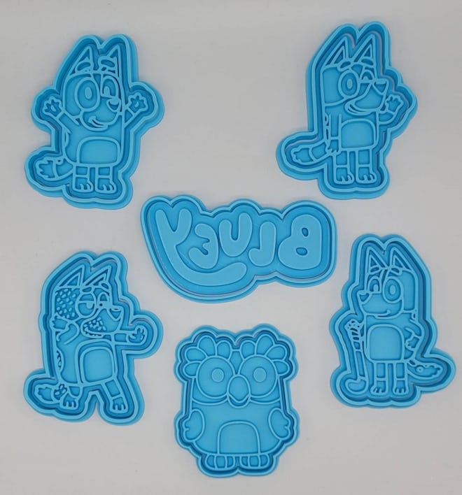 Six cookie cutters on a table; cutters in the shape of characters from "Bluey"