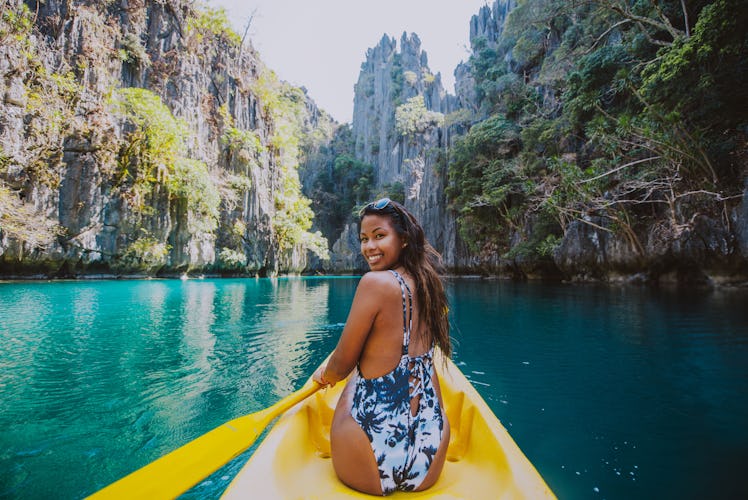 Young woman paddling in a yellow bathing suit before posting Instagram pics with kayaking quotes, ka...