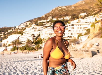 Young woman in a bikini, laughing at beach and sea puns while on vacation.