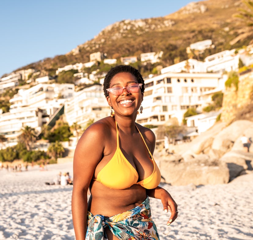 Young woman in a bikini, laughing at beach and sea puns while on vacation.