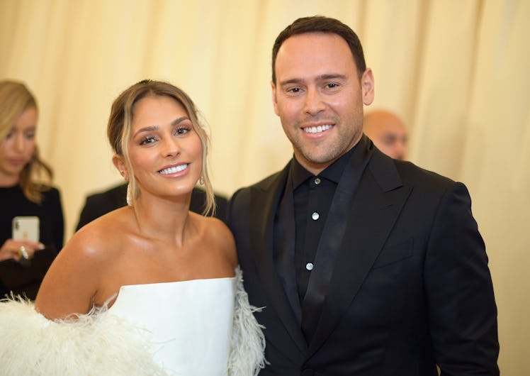 Scooter Braun in a black suit and shirt and Yael Cohen in a white feather dress