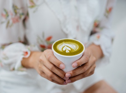 Young woman holding a cup of matcha, thinking of matcha puns, quotes, and captions to post on Instag...