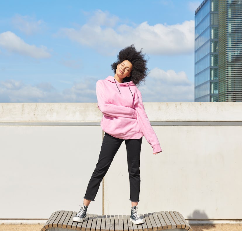 Young woman in a pink hoodie having the best week of July 26, 2021, per her zodiac sign's horoscope.