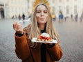 Young woman eating Belgian waffles outside before posting a foodie pic on Instagram with waffle quot...