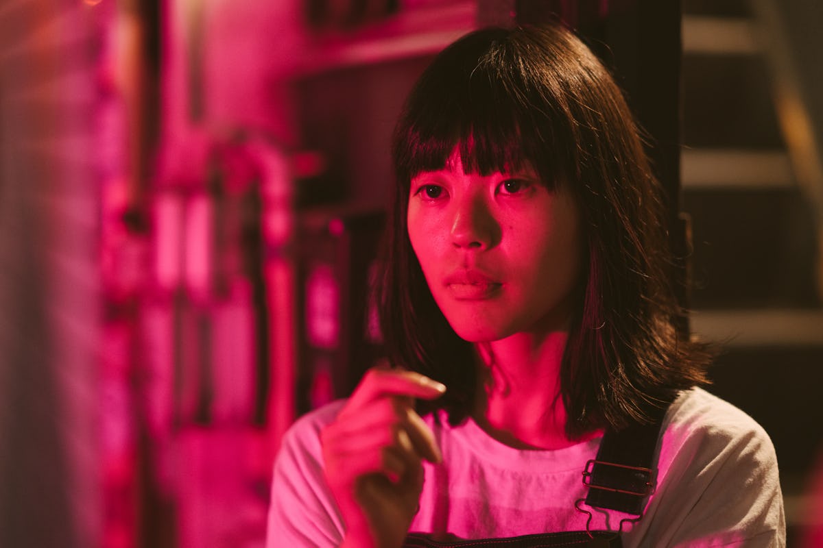 Young woman lit up by red neon lights to show the Pluto in Scorpio generation.