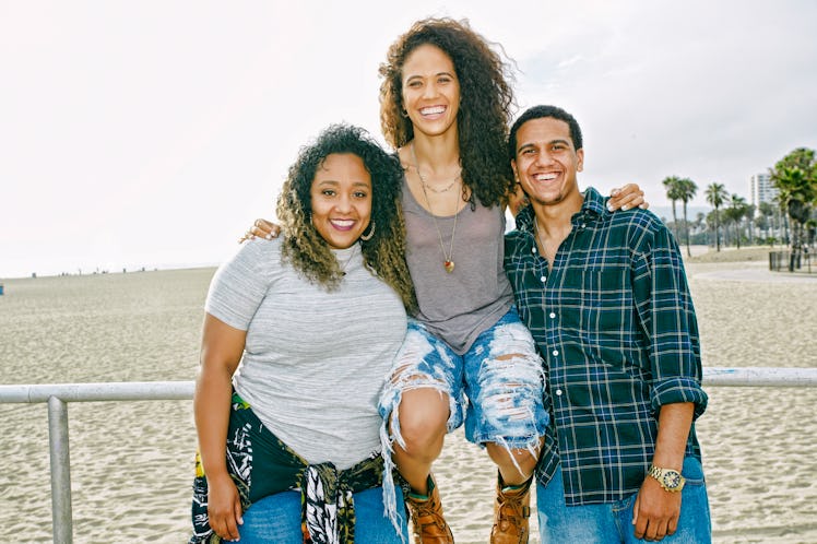 3 siblings smiling at the beach on National Siblings Day before posting a pic on Instagram with a si...