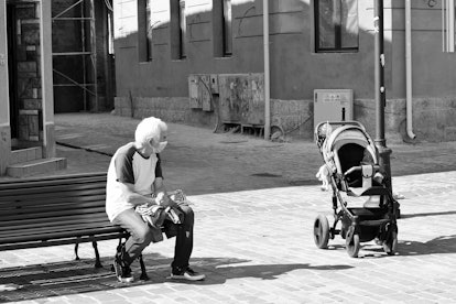 A masked older man keeping a safe distance from a baby in a stroller