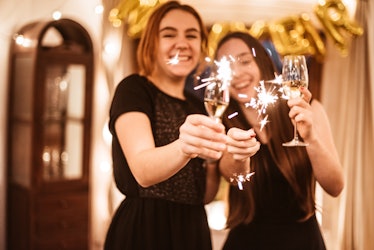 Young couple toasting with Champagne on New Year's Eve before posting on Instagram with new year cou...